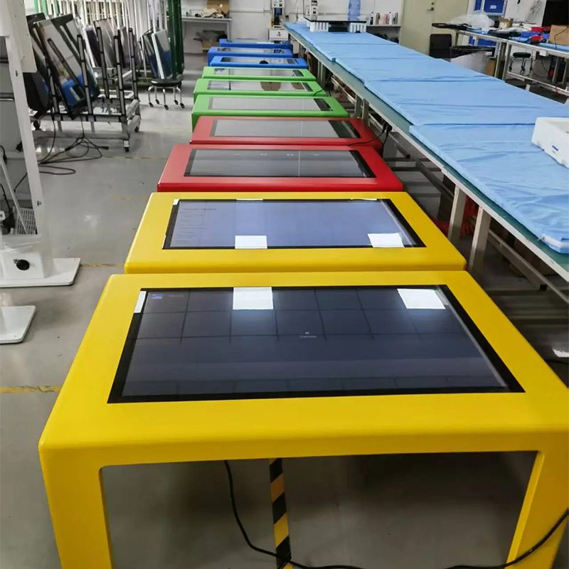 Interactive touch screen tables in red, blue, and green, with the user interface displayed